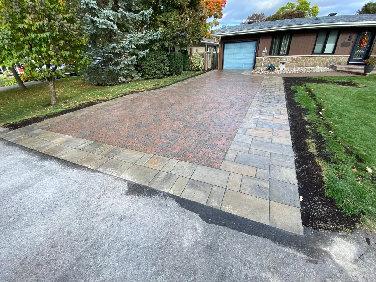Multi-tone paver driveway bordered in cut stone